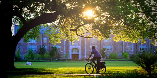 student riding bike on campus